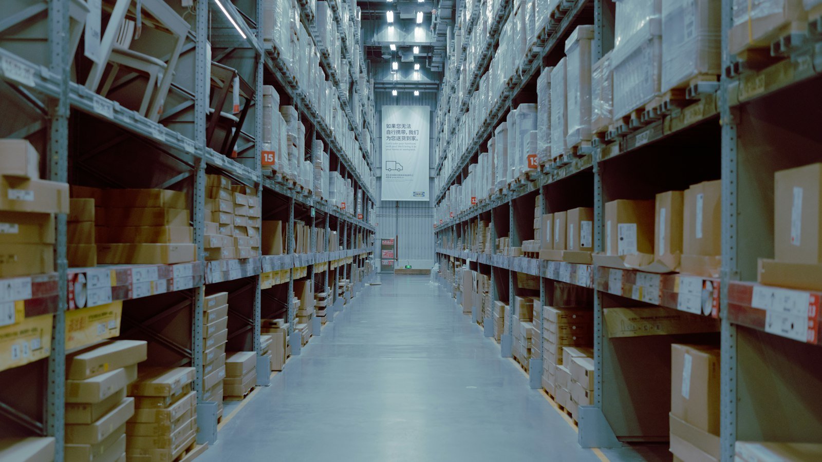 Warehouse aisle with tall shelving stocked with boxed spare parts inventory