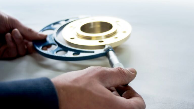 Inspector measuring a brass flange with a micrometer during quality control